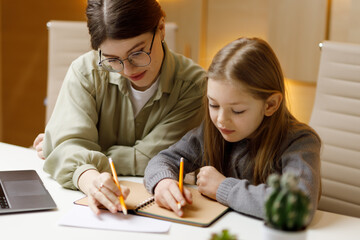 A young woman teacher conducts a private lesson with a little girl, a child psychologist.