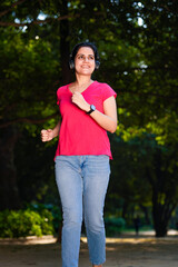 young indian woman with earphones listening music during jogging at park.