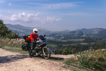 Motorbiker travelling, summer day, motorcycle off road, the driver with adventure, touring motorbike with side bags, extreme tourism, sport weather clothes, Carpathians mountains Ukraine