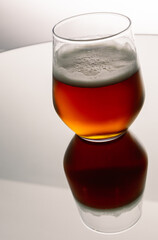Vertical shot of glass of beer with the reflection on table