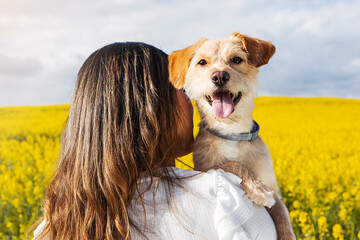 Closeup shot of a back view of a young female with her retriever in the field