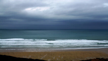 Beautiful view of sea waves on a beach with a storm brewing on the horizon