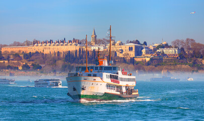 Fototapeta premium Water trail foaming behind a passenger ferry boat in Bosphorus on the background famous historical Topkapi Palace - Istanbul, Turkey