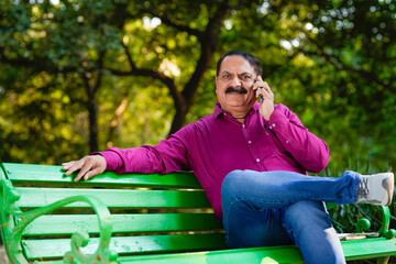 indian man talking on smartphone at park.