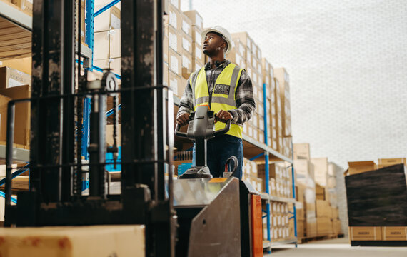 Man in a reflective jacket driving a forklift in a warehouse