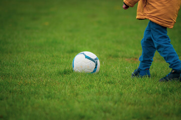 Child playing with a soccer ball on a green field