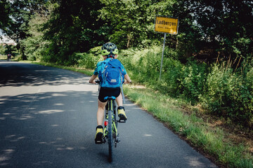 Junge passiert das Ortsschild von Ladbergen während einer Fahrradtour durch das Münsterland in den Sommerferien, Deutschland
