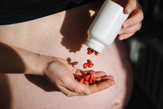 Lutein. Pregnant woman take vitamins daily, multivitamins. Closeup photo of female hands hold supplements with a white bottle. Place for text. Pregnancy, treatment, medicine healthcare concepts.