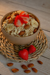 Oatmeal porridge with strawberries and nuts on light wooden background