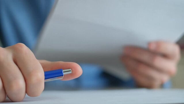 Annoyed boss clicks pen while examining enterprise documents, closeup