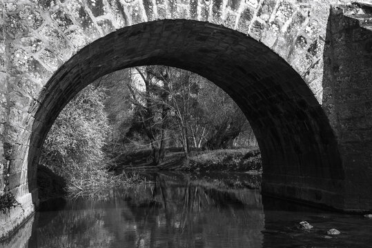View through arch of Roman bridge on old royal road from Paris to Sens over Yerres river near Brie-Comte-Robert. Built in 17th-18th c. recalls architects name, Romains brothers. Black white photo