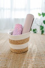 A pink foam massage roller and yoga mat at floor in living room. Foam rolling is a self myofascial release technique. Gym fitness equipment.