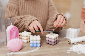 woman making candles at home, close up of female hands cutting wick of bauble candle - obrazy, fototapety, plakaty