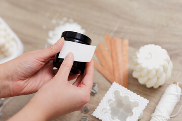 Woman hand holding handmade candle jar with white label with space for text