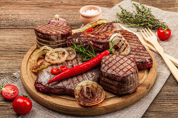 Grilled set of various steaks with vegetables. Ribeye, eye round, flank and striploin steaks