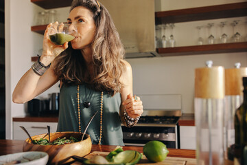 Vegan woman drinking green juice in her kitchen