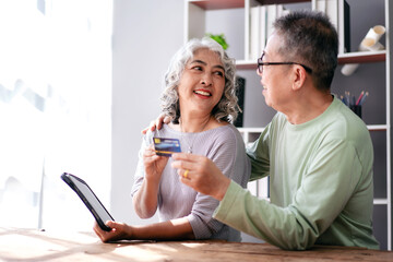 Senior couple holds credit card and digital tablet to buying lif