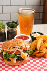 Vertical closeup shot of a cheeseburger served with fries, sauces and a drink