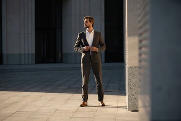 Fototapeta na wymiar Elegant handsome man in classic suit standing near the office building.