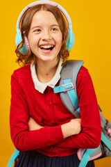 Happy schoolgirl with backpack, headphone having fun
