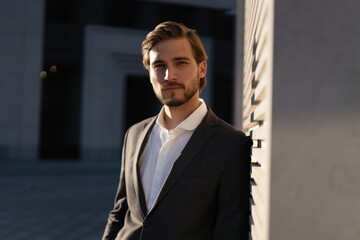 Elegant handsome man in classic suit standing near the office building.