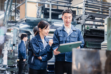 タブレットを見ながら工場で議論をするスタッフ