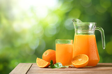 Natural squeezed orange juice on woodentable with blur green background.
