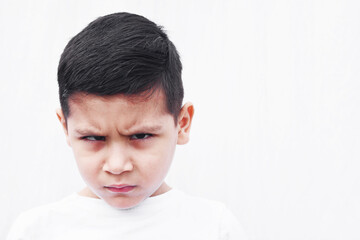 Angry little latin boy with frowned face.