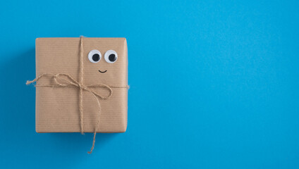 Banner with brown craft gift boxes with smilling face on blue background. Space for your text, horizontal.