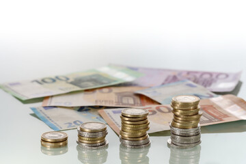 Stacks of Euro coins and Euro banknotes on shiny surface