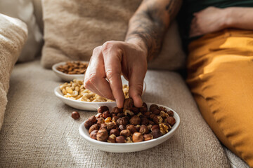 Close-up shot of a tattooed man picking up hazelnuts.