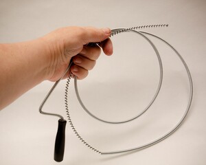 Hand holding a spiral drain unblocker on isolated white background