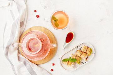 Glass teapot of natural seasonal healthy organic cranberry tea. Turkish sweet baklava with honey...