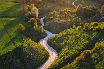 Beautiful spring landscape among green hills. Charming winding road between green nature. Photo taken in Grodzisko - Stradow, Poland.