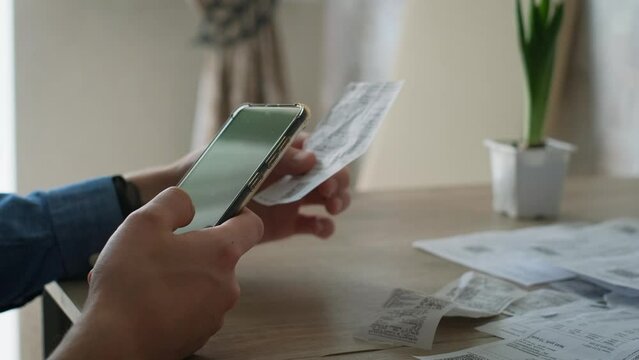 Man pays bills from smartphone scanning qr code of receipts
