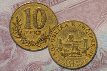 Closeup shot of golden Albanian lek coin from both obverse and reverse sides on a banknote