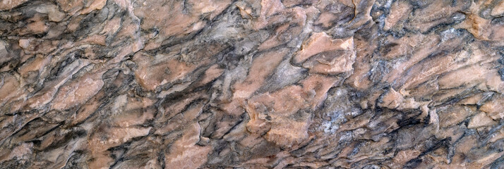 Abstraktes Muster in braun, grau und schwarz in einer groben Steinoberfläche in Panorama Nahaufnahme