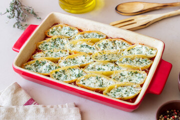 Baked pasta stuffed with cheese and spinach in tomato sauce. Vegetarian food. Italian food.