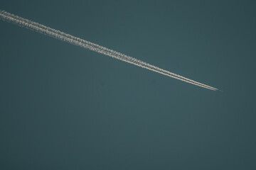 plane flying through the blue sky with condensation