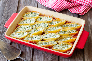 Baked pasta stuffed with cheese and spinach in tomato sauce. Vegetarian food. Italian food.