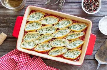 Baked pasta stuffed with cheese and spinach in tomato sauce. Vegetarian food. Italian food.