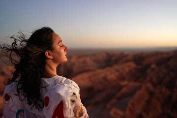 rear view young latin woman standing at the viewpoint over the Valle de la Luna or valley of the...