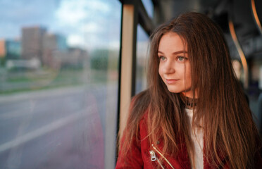 Obraz premium Beautiful Young Girl is Going in Trolley in Vilnius Old Town, Lithuania. Wearing Red Jacket. Beautiful Spring Day. Smiling.