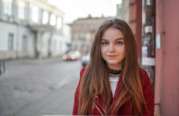 Fototapeta na wymiar Close up Face of Beautiful Young Girl in Vilnius Old Town, Lithuania. Wearing Red jacket and Black Trousers. Beautiful Spring Day