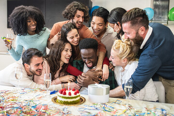 Group of friends hugging the young African American celebrated on his birthday, manifestations of joy friendship and affection of a multiracial group
