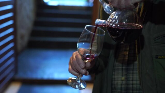 Sommelier or winemaker pouring and waving young red wine in a glass 