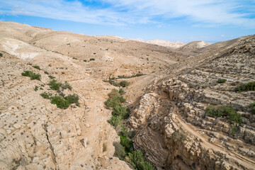 Fototapeta na wymiar Israel. Prat River. Wadi Qelt valley in the West Bank, originating near Jerusalem and running into the Jordan River near Jericho and the Dead Sea. Nahal Prat, in Judaean Desert. Nature, Landscape