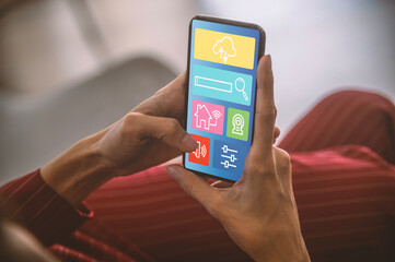 Woman holding a smartphone with smart home screen.