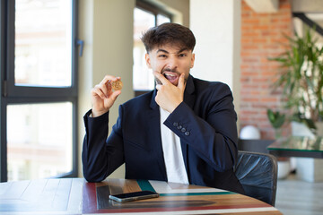 young handsome man with mouth and eyes wide open and hand on chin. virtual money concept