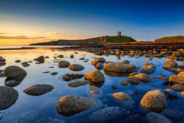 Dunstanburgh Castle at dawn from Embleton Bay, Northumberland, England